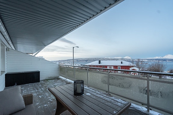 Terrassedekke er av trevirke, rekkverk er av stål og glass med håndlist av trevirke.