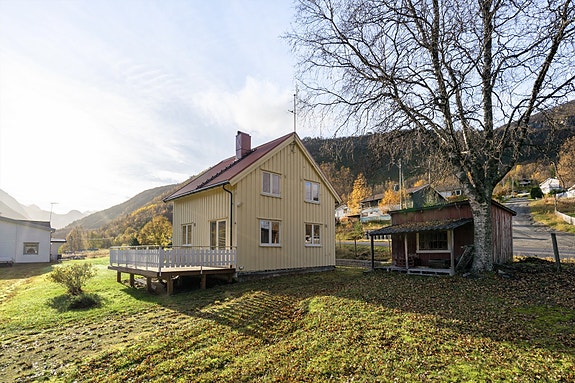 Eneboligen har en klassisk fasade med stor veranda og en romslig tomt som omgis av vakker natur og fjell