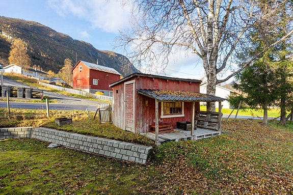 Uthus og hage med nydelig utsyn mot fjellene - her er det lett å se for seg rolige dager og sene sommerkvelder under trærne