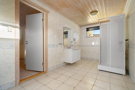 Romslig baderom med flislagt gulv, dusjkabinett og baderomsinnredning