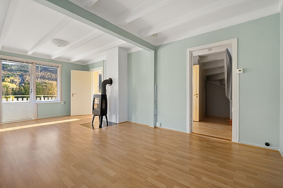 Lys og romslig stue med store vinduer som slipper inn rikelig med dagslys og gir flott utsikt mot fjellene