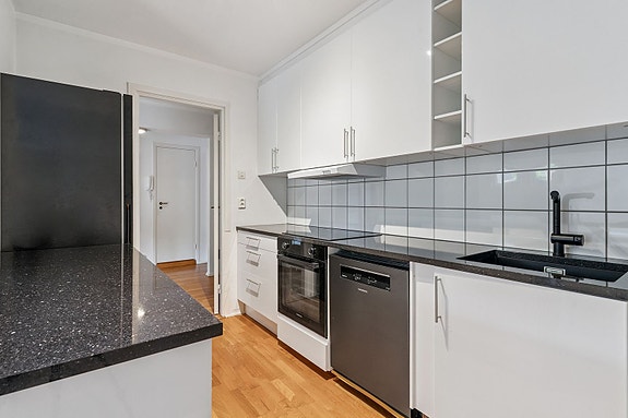 Pent kjøkken med splitter nye hvitevarer og benkeplate.