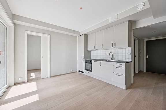 Stue og kjøkken i åpen løsning. Kjøkkenet har integrerte hvitevarer