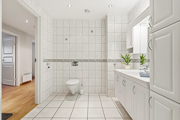 Badet har veggehengt toalett og balansert ventilasjon.