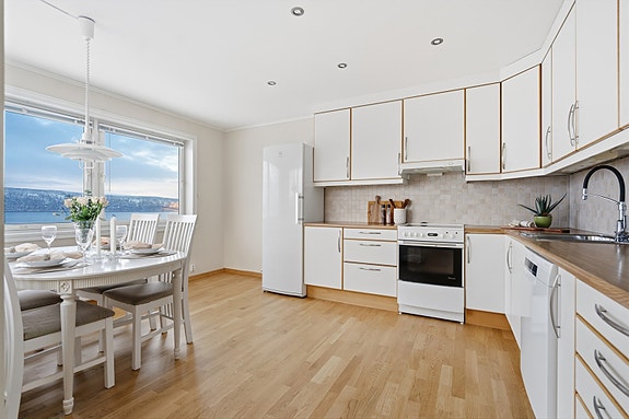 Kjøkkenet har lyse, slette fronter med takhøye overskap.