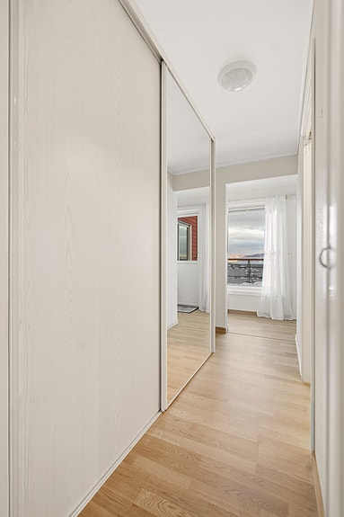 Gang mellom gang og kjøkken/stue inneholder en stor skyvedørsgarderobe.