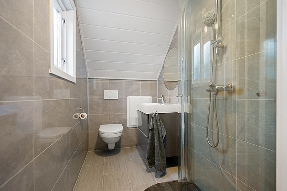 Flislagt bad i 2. etasje med praktisk dusjløsning, servant og vegghengt toalett