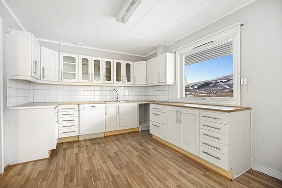 Lys kjøkkeninnredning med profilerte fronter og benkeplate av laminat.