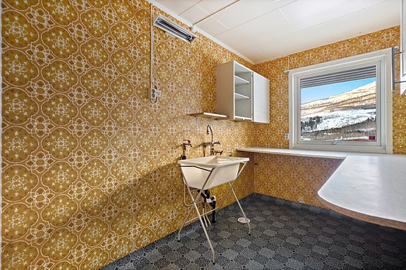 Praktisk vaskerom med opplegg for vaskemaskin, tørkeskap, skyllekar, benk og overskap.