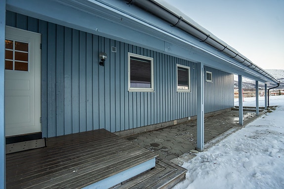 Overbygget gangvei med betongheller frem til inngangsparti.