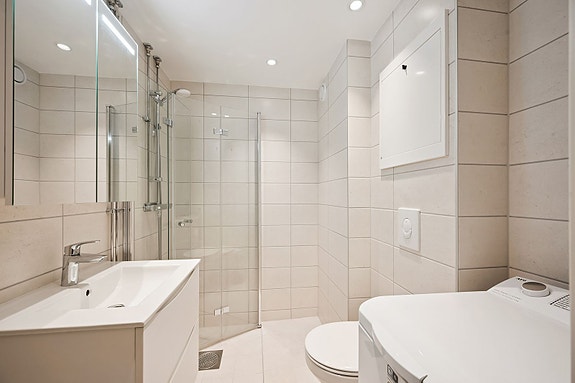 Moderne baderomsinnredning med funksjonell lagringsplass og spotlights.