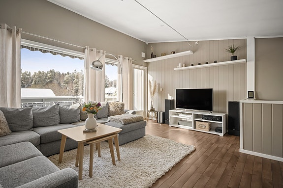 En lys og pen stue med store vinduer.