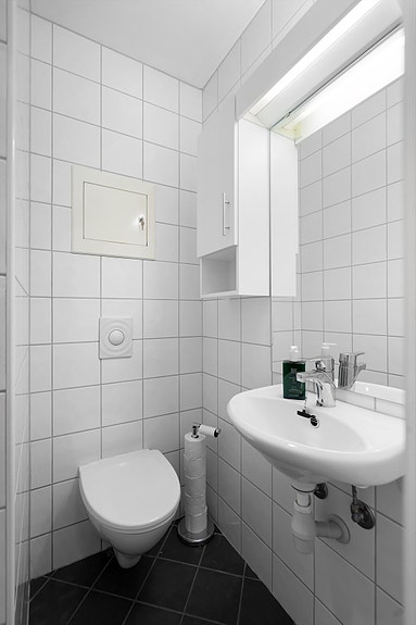 Flislagt bad i 1. etasje med vegghengt toalett, dusj og servant