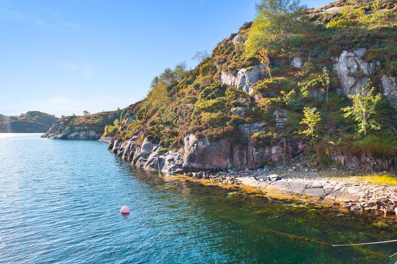 Eiendomsmegler Merete Seim v/EiendomsMegler 1 har gleden av å presentere en naustetomt på Kausland (Foto: Mats Lie)