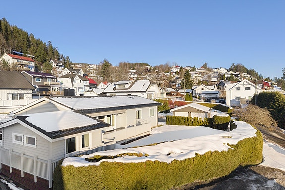 Tomten er opparbeidet med plen og beplanting. Beleggningstein i carport.