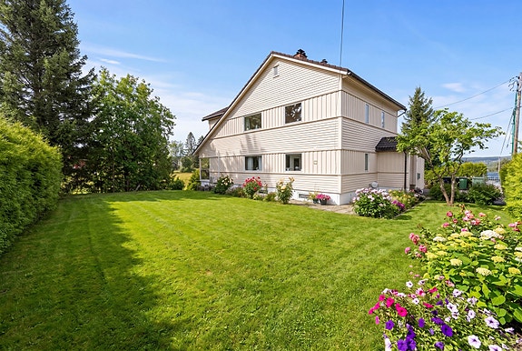 Velkommen til Bråteveien 117 - En stor og innholdsrik enebolig over 3 plan med gode utleiemuligheter og generøse, solrike uteområder. (Bildet er AI-redigert).