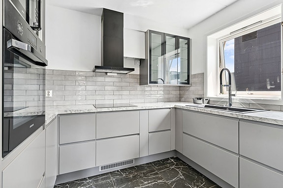 Separat kjøkken med moderne innredning, rikelig med skapplass og tilhørende hvitevarer.