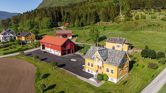 DNB Eiendom v/Bendik Joten Tangen har gleden av å presentere Øvstedalsvegen 11 - Eiendommen strekker seg over et stort areal med asfaltert tun og grønne enger, omkranset av majestetiske fjell.