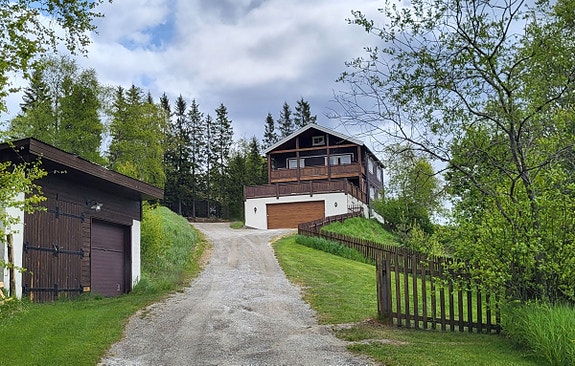 Huset sett fra E136. Dobbel garasje ved veien og dobbel garasje bygd inntil huset.