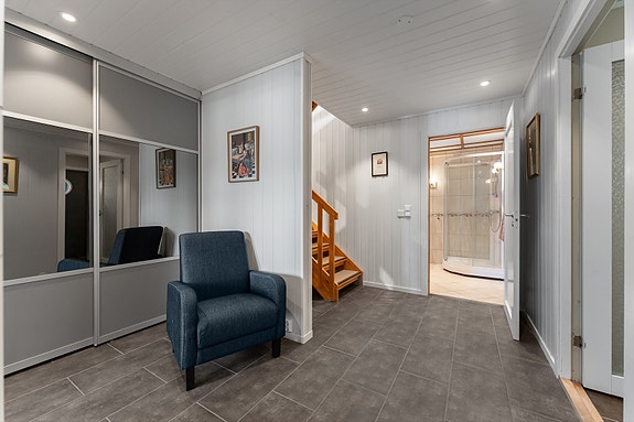 Praktisk hall med skyvedørsgarderobe og rikelig med ryddig oppbevaringsplass. Herfra leder trappen opp til 2. etasje.