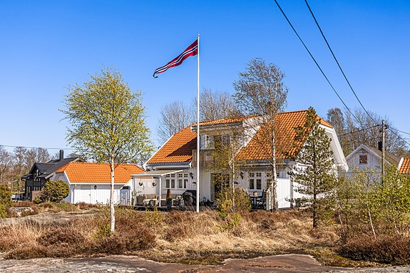 Tomten er en kombinasjon av asfaltert gårdsplass, naturtomt med svaberg og beplantning.