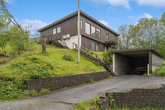 Eiet tomt er oppgitt til cirka 1 458 m², med skrånende terreng rundt boligen.