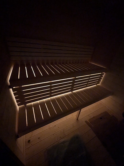 Belysning under benk i badstue.