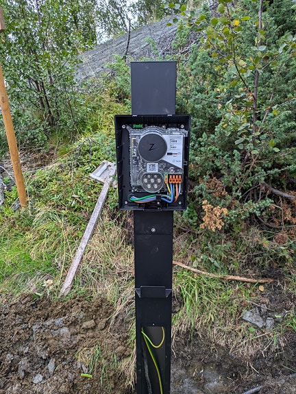 Montering av elbil lader på søyle langt fra hytten den tilhører.