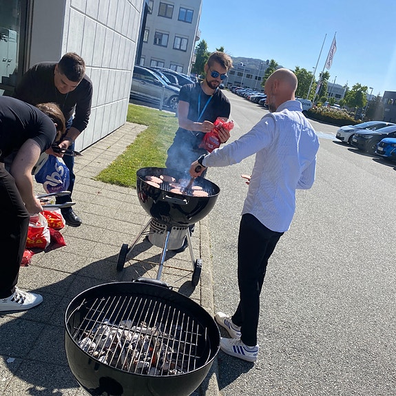 Sjefen griller burgere til alle ansatte på parkeringsplassen utenfor kontoret. Finværet må nytes!