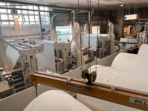 Konverteringsavdelingen har to separate produksjonslinjer som lager både to og trelags produkter alt etter hva kunden bestiller. Vi bruker traverskraner til å løfte de tunge rullene inn i maskinene.