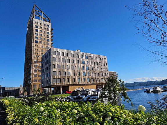 Norwegian Wood Cluster leier lokaler i 6. etg i bygget rett i forkant av Mjøstårnet (som åpnet som verdens høyeste trebygg i 2019)