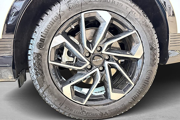 Svart lettmetallfelg med detaljrikt design og Continental-dekk.