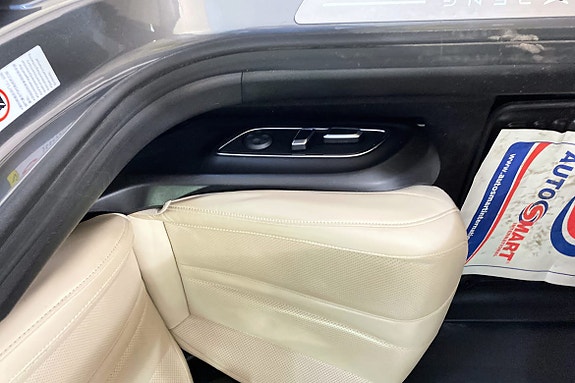 Dørpanel i beige skinn med praktiske kontrollknapper og detaljer.