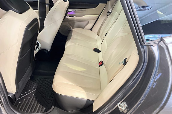 Romslig baksete i beige med komfortabel innredning og tepper.