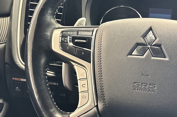 Ergonomisk ratt med multifunksjonsknapper og tydelig Mitsubishi-logo.