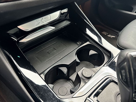 Konsoll med koppholdere og stilrent high-gloss sorte detaljer.