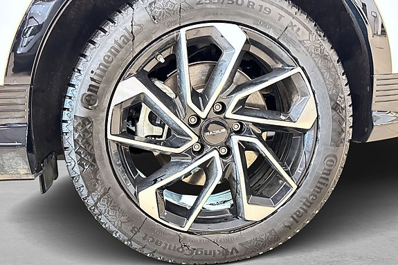 Svart lettmetallfelg med detaljrikt design og Continental-dekk.